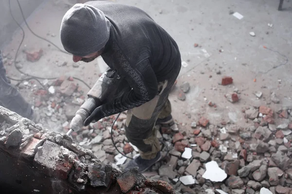 一个工人用千斤顶砸碎砖墙 建造和修理他的房子 — 图库照片