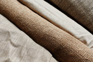 Natural fabrics from organic colors of flax and cotton in rolls, homespun textile handmade. Burlap and canvas for eco, rustic, boho, hygge decor clipart