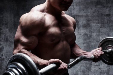 Seksi kas vücut geliştirmeci karanlık bir arka plan karşı ağır deadlifts yapıyor. Bir halter ile atletik pompalanmış erkek vücudu