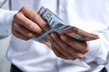Tenge kağıdı. Gömlekli işadamının elleri Kazak parasını yakınsa.