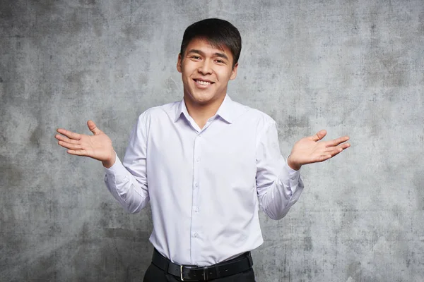 Young attractive Asian Kazakh smiling and spread his arms in surprise, businessman dressed in a white shirt isolated in studio
