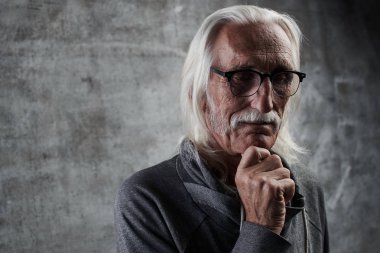 Yaşlı gri saçlı Beyaz emekli adam hayatı düşünüyor. Bıyıklı ve düşünceli yüz ifadesi ile gözlük büyükbaba çenesini tutar