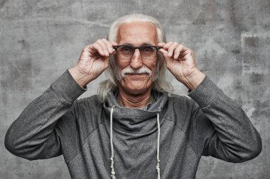 Gri saçlı ve bıyıklı yaşlı bir adam gözlükdaha iyi görür, kör, gülümsüyor ve iyi bir vizyon sahiptir, bir duvara karşı çekilen bir stüdyo fotoğraf