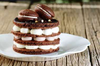 Ahşap masada beyaz plaka bisküvi, beze ve macaroons ile ev yapımı çikolatalı kek pişirme. Şenlikli tatlı tatlı Doğum günü dekorasyon Makaron