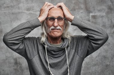 Gözlüklü eski gri saçlı Kafkas dedesi başını tutar, yüzünde ağrı grimace, kötü haber, olay, üzgün, hayal kırıklığına uğramış, gürültülü komşular
