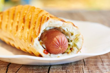 Beyaz tabakta iştah açıcı hotdog yakın çekim. Sosis hamuru, fast food