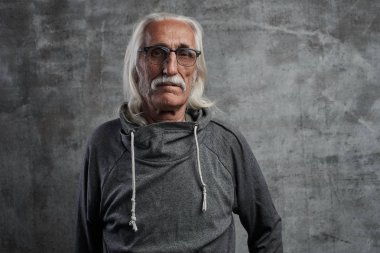 Gözlük ile yaşlı gri saçlı Kafkas adam emeklinin portresi. Gri arka planda kamera bakarak bıyık ve ciddi yüz ile Cool Büyükbaba