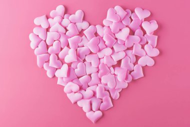 Aşk ile Sevgililer Günü için pembe bir arka plan üzerinde birçok hacimsel kalpler