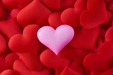 Pink heart on the background of many red hearts. The concept of Valentine's Day, love, treason, polygamy clipart