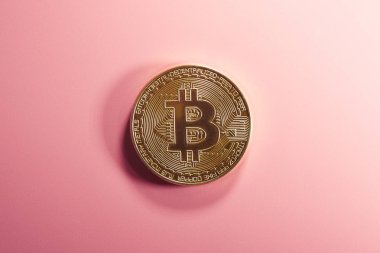 Pembe arka planda Bitcoin fiziksel altın sikke. Dijital kripto para birimi kavramı