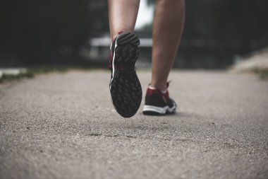 Kaldırımda spor ayakkabılarla hareket halindeki kadın bacakları. Rahat spor ayakkabı kavramı, koşu, fitness, koşu