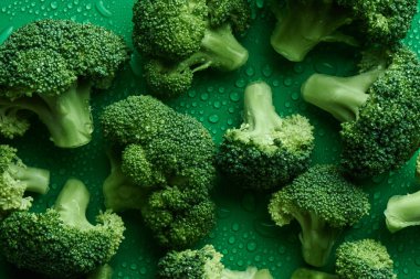 Yeşil arka planda taze çiğ brokoli, üst görünümü. Sağlıklı gıda kavramı, diyet, sulforaphane, cruciferous sebze