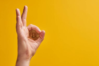 Sarı arka planda fiziksel para bitcoin ile el, jest 