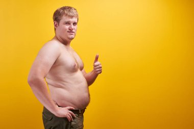 Büyük şişman göbeği ve çıplak vücudu olan kocaman genç bir adam. Obezite kavramı, hızlı ve abur cubur, spor, liposuction, ürün veya metin için boş alan ile kilo kaybı
