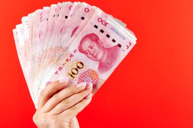 Kırmızı bir arka plan üzerinde bir kadın elinde Çin yuan para Rmb banknotlar bir yığın