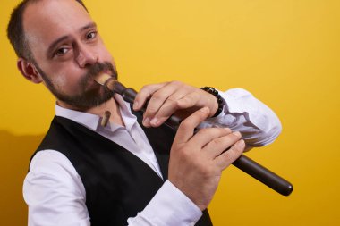 Profesyonel müzisyen adam sarı bir stüdyoda bir boru closeup oynuyor. Halk rüzgarlı çalgı, flüt