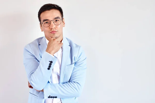 Portrait of smart thinking Kazakh man in glasses dressed in business suit in the office on white background. Asian handsome businessman