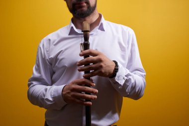 Profesyonel müzisyen adam sarı bir stüdyoda bir boru closeup oynuyor. Halk rüzgarlı çalgı, flüt