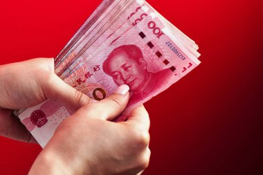 Kırmızı bir arka plan üzerinde bir kadın elinde Çin yuan para Rmb banknotlar bir yığın