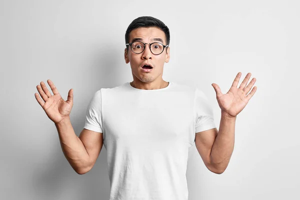 ショックを受けたアジア人男性は カジュアルでメガネをかけた口を開け 手を上げてカメラを見る 白いスタジオの背景に驚いた若いカザフスタンの学生の男 — ストック写真