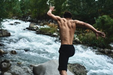 Kazak kaslı atlet adam trenler ve doğada nehir tarafından egzersizleri. Asyalı yakışıklı açık havada aşırı fitness egzersiz yok