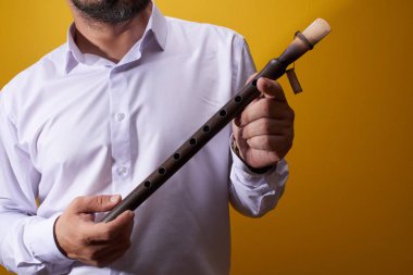 Profesyonel müzisyen adam sarı bir stüdyoda bir boru closeup oynuyor. Halk rüzgarlı çalgı, flüt