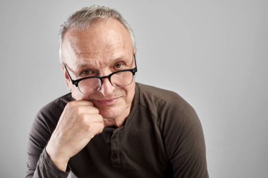 Stüdyoda beyaz bir arka plan üzerinde gözlük şık bir modern yaşlı adam Portresi. Tecrübeli patron. Tür bakmak