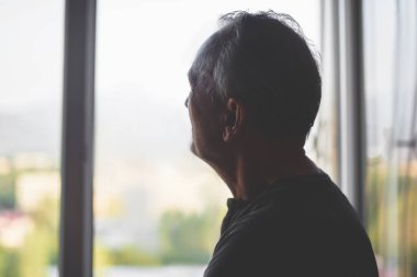Pencere arka planı olan yaşlı bir adamın silueti. Yaşlı. Depresyon emeklisi. Emeklilik yalnızlık.