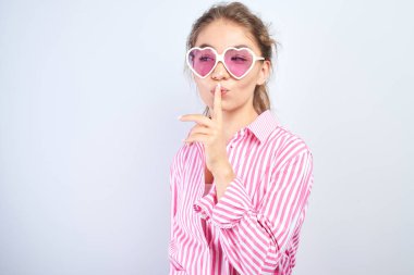 Asyalı Kazak kız dudaklara işaret parmağını koydu, shh. Kavram sessiz, gizli, sessizlik tutmak