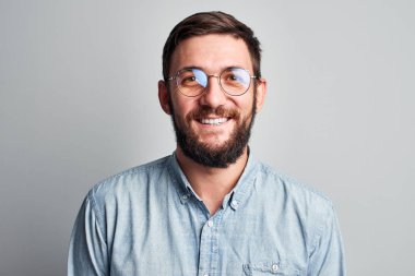 Beyaz bir duvara izole karşı rahat giyinmiş rahat gülümseyen diş gözlüklü otantik bir kafkas sakallı adamın samimi yüz portresi
