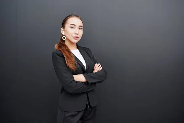Asian Kazakh businesswoman realtor in suit on black wall background