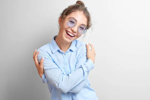 Portre dostu gülümseyen Asyalı kız, neşeli bir şekilde kendine sarılıyor ve izole beyaz bir arka planda gülüyor.