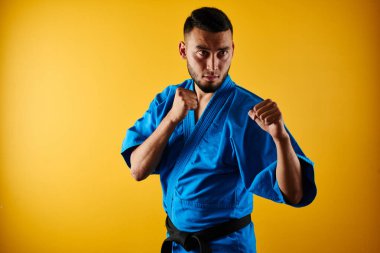 Kimono üniformalı Asya Kazak karate savaşçı izole kopya alanı ile sarı arka plan üzerinde mücadele
