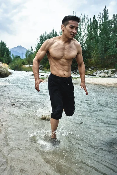 Asian athlete on a morning run on the river, Kazakh jogger in nature close-up