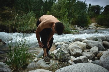 Kazak kaslı atlet adam trenler ve doğada nehir tarafından egzersizleri. Asyalı yakışıklı açık havada aşırı fitness egzersiz yok