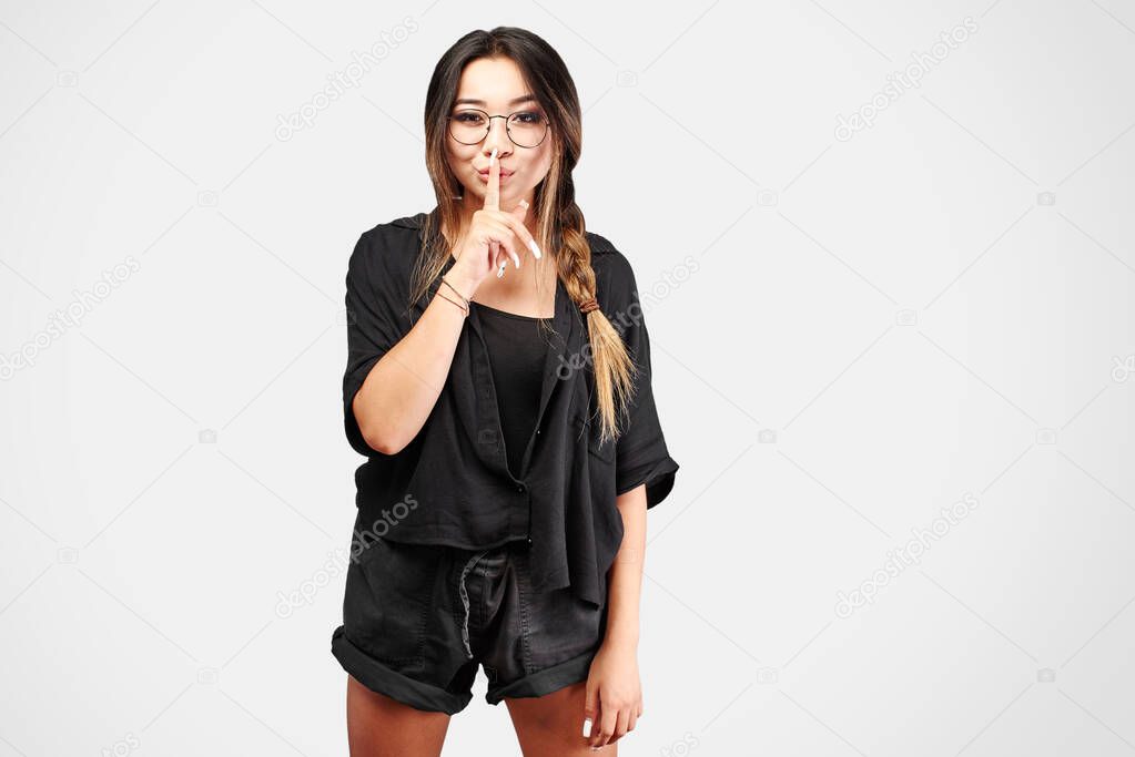 Asian Kazakh girl put her index finger to lips, shh. Concept keep quiet, secret, silence