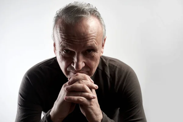 Portrait of a stylish modern elderly man on a white background in the studio. Senior boss thinking in a pensive pose