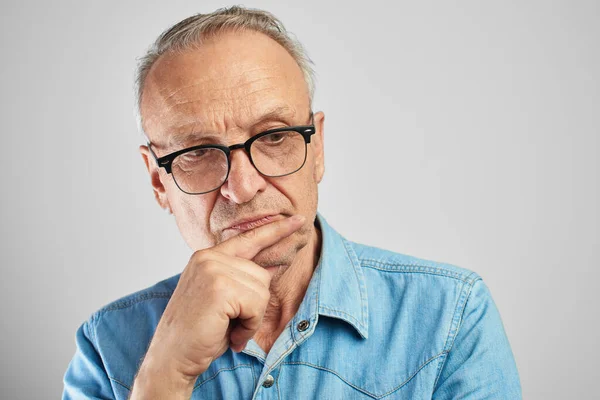 Portrait of a stylish modern elderly man in glasses on a white background in the studio. Senior boss thinking in a pensive pose