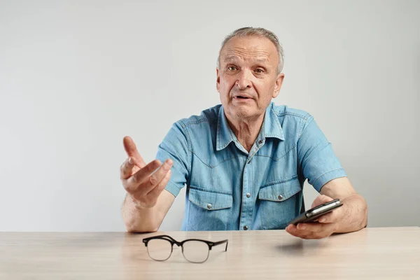 Аутентичный Фото Портрет Пожилого Человека Сидящего Столом Мобильным Телефоном Руке — стоковое фото