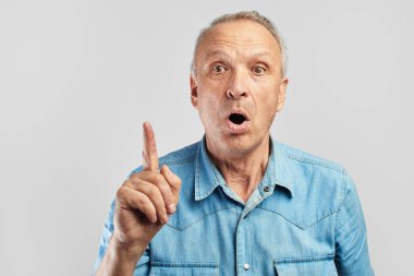 Parmağını kaldırmış ve ağzı açık yaşlı bir vatandaşın bir fikri var. Yaşlı adam beyaz arka planda inanılmaz bir şey fark etti.