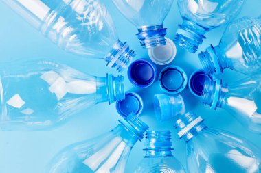 Mavi arka planda izole edilmiş, farklı tipte boş su şişeleri var. Plastik üretim ve işleme kavramı