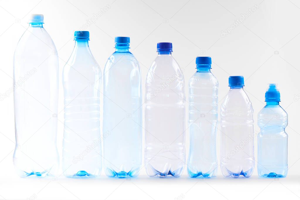 Set bottles of mineral water different types and sizes stand in row isolated on white. Plastic production and processing concept