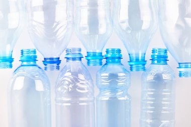 Farklı tipte boş su şişeleri beyaz, üst görünümde izole bir şekilde yatar. Plastik üretim ve işleme kavramı