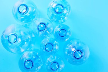 Mavi arka planda izole edilmiş, farklı tipte boş su şişeleri var. Plastik üretim ve işleme kavramı