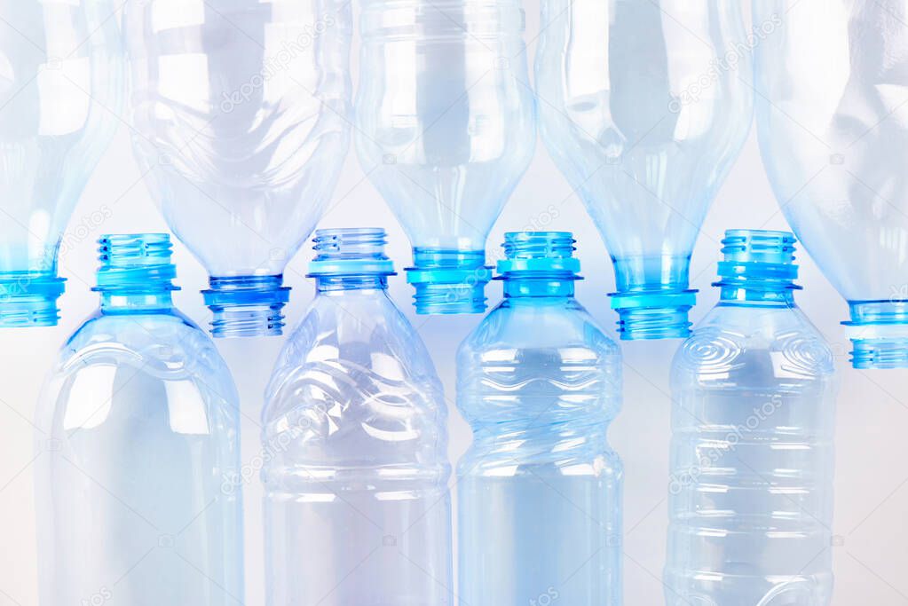 Set of empty different type water bottles lie isolated on white, top view. Plastic production and processing concept