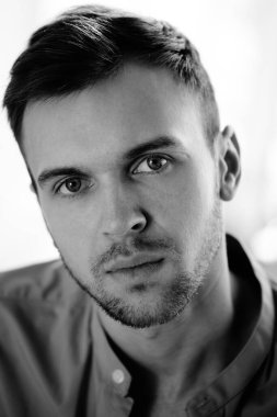 Yakışıklı, başarılı, beyaz beyaz bir adamın siyah beyaz portresi kameraya bakar.