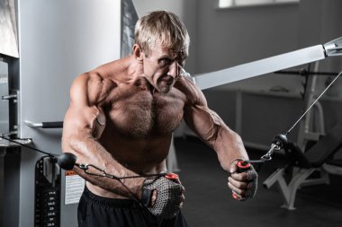 Spor salonundaki TRX döngüleri üzerinde çalışan kaslı, yetişkin, vahşi bir adam. HIIT egzersizleri yapan Kafkas özgün vücut geliştiricisinin portresi
