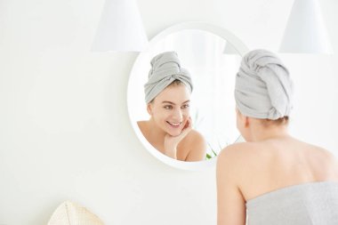 Beyaz banyoda kafasında havlu olan genç bir kızın portresi aynada yüzüne dokunuyor ve gençlik ve su kaybından zevk alıyor. Doğal güzellik, sorunlu cilt bakımı