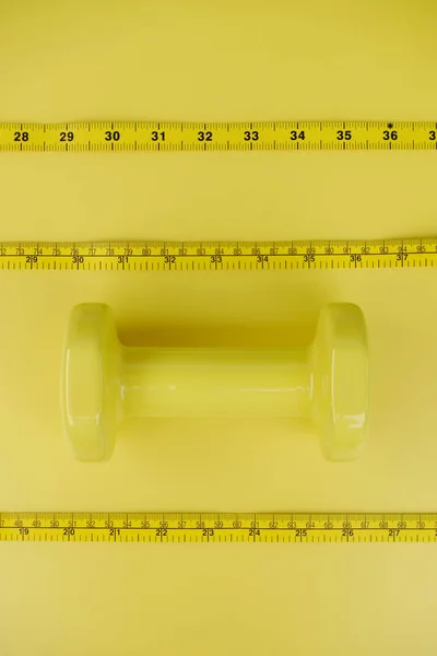 Fitness concept dumbbell and measuring tape for background