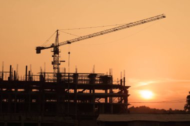 Siluet vinç ve binaların yapım aşamasında akşam gökyüzü karşı bina.